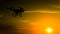 Quadrocopters silhouette against the background of the sunset. Flying drones in the