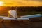 Quadruple aircraft parked at a private airfield. Rear view of a plane with a propeller on a sunset background.