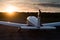 Quadruple aircraft parked at a private airfield. Rear view of a plane with a propeller on a sunset background.