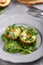 Quail eggs baked in avocado. Avocado egg boats served with spinach leaves on gray plate. Ketogenic, keto low carb diet