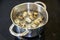 Quail eggs are boiled in a small saucepan on a black background, on an electric stove