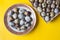 Quail eggs container and fresh eggs on yellow background. Top view