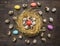 Quail eggs in a nest with colorful decorative eggs for Easter laid out around wooden rustic background top view close up