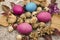 Quail eggs and painted eggs withamong dry buds of roses and dry leaves, cones with a knitted  white napkin  on dark polished boar