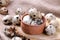 Quail eggs in a wooden bowl on a brown wooden stand on a brown background