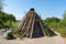 Quaint wooden hut is situated in a sprawling field  with a few trees in the background