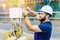 A qualified electrical engineer sets up a control and measuring device at an industrial facility on a summer day.