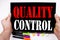 Quality Control text written on tablet, computer in the office with marker, pen, stationery. Business concept for Product Improvem