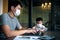 Quarantine asian man and children wearing protection mask working on computer at home while covid-19 virus inflected global