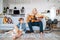 Quarantine Family time: Little and older brothers at living room together.Teen playing acoustic guitar, smiling little boy playing