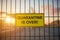 Quarantine is Over sign on a fence with blured city view on a background at sunset