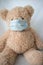 Quarantine, threat of coronavirus. Sad child and his teddy bear both in protective medical masks sits on windowsill and