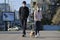 Quarantine in Ukraine. A young couple in protective masks walks the dog