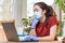 Quarantine.A young woman in a medical mask and gloves is typing on her laptop, looking bored. Home environment.The concept of