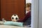 The quarantined girl in self-isolation sits with a ball at the front door