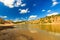 Quarry or lake or pond with sandy beach, water, trees and hills with cloudly sky