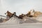 Quarry machines and piles of gravel over blue sky. Stone crushing and screening plant