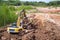 Quarry with red clay. Big yellow excavator extracts clay with stacks in a truck. With place for text