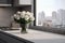 Quartz countertop of monochromatic kitchen with bouquet of white roses in vase, window and view of the city, copy space.