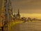 Quays of the harbor of Antwerp, with ld industrial cranes and cathedral in th background in warm sunset light