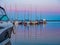 Quayside with jetty full of sailing yachts and motorboats, calm pink and blue dusk landscape