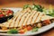 Quesadillas triangles with beef meat and vegetables on plate on blurred background