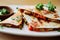 Quesadillas triangles with beef meat and vegetables on plate on blurred background