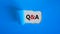 Question and answer symbol. Concept words `Q and A - question and answer` appearing behind torn blue paper. Beautiful blue