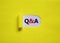 Question and answer symbol. Concept words `Q and A - question and answer` appearing behind torn yellow paper. Beautiful yellow