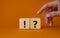 Question mark and exclamation mark symbol. Question mark and exclamation mark on wooden cubes. Businessman hand. Beautiful orange