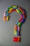 Question mark is lined with wooden multicolored clothespins on a gray background
