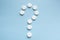 Question mark made of medicine tablets on a blue background. Isolated