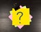 Question mark on a sticky note on wooden background