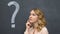 Question mark written on blackboard, pensive woman thinking, making decision