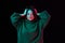 Questioning mood, grimacing. Young girl in cozy sweater over dark background in neon light. Concept of emotions, youth