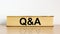 Questions and answers symbol. Book with word `Q and A, questions and answers` on beautiful wooden table, white background.