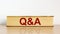 Questions and answers symbol. Book with word `Q and A, questions and answers` on beautiful wooden table, white background.