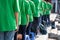 Queue of Asian teenagers in green t-shirt uniform standing in line