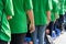 Queue of Asian teenagers in green t-shirt uniform standing in line