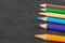 Queue of colorful pencils on the black ground