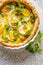 Quiche with with boiled eggs and leeks sprinkled with fresh lambs lettuce served in casserole dish on a white table