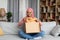 Quick purchases in online store. Satisfied black muslim lady opening cardboard box, taking clothes from parcel