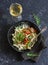 Quick ratatouille pasta and a glass of white wine on dark background, top view.