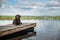 A quiet, calm, summer lake and a dog on a wooden bridge.