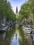 Quiet channel with boats on a sunny day. Zuiderkerk protestant church in the background.Amsterdam, the Netherlands