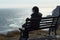 Quiet contemplation black jacketed girl on a cliff bench by sea
