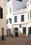 Quiet empty cobbled street with white painted typical houses in bright summer sunlight with a bicycle outside an old doorway