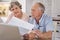 Quiet house, thunder in our hearts. an elderly couple going over paperwork together at the table at home.