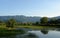 Quiet lake creek on the background of mountains, blue cloudless sky and green trees