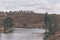 Quiet lake surrounded by hills and trees with an old partially sunken wooden bridge